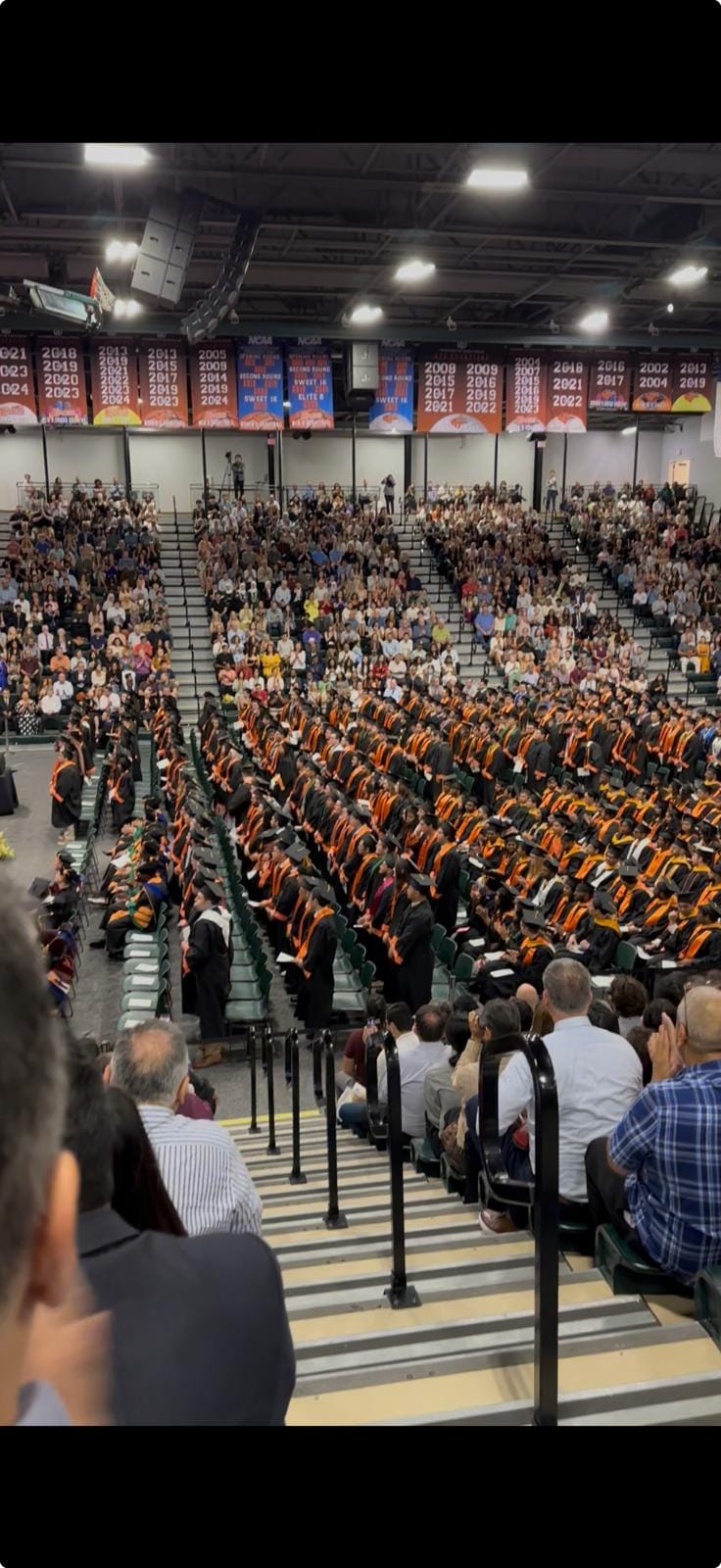A packed arena at commencement, a sea of graduation gowns.